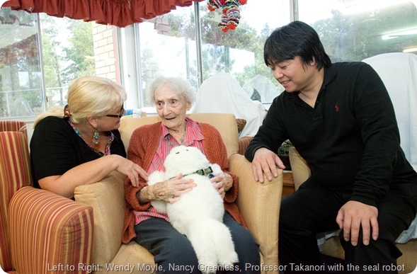 Professor Takanori is in Australia from Japan to meet with Professor Wendy Moyle to talk about the robots for dementia. At Sinnamon Park Retirement Village.L to R Wendy Moyle, Nancy Greenless, Professor Takanori with the seal robot